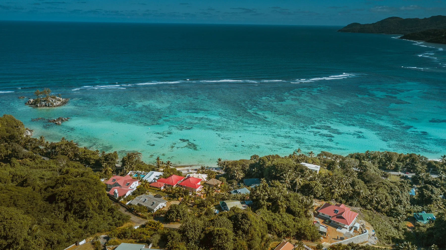 Turquoise water beside a green Seychelles coastline